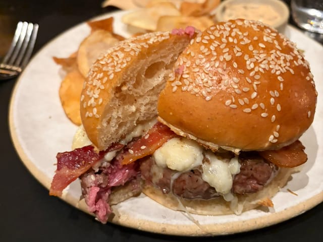 Halved medium-rare Tavern Burger with bacon, melted cheese and potato chips at Gramercy Tavern